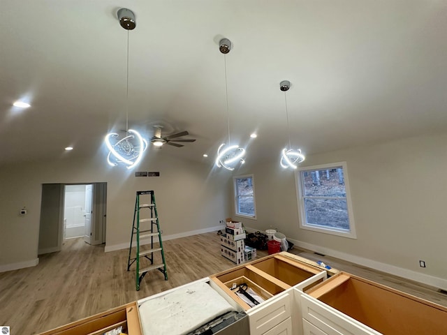 interior space with light wood finished floors, lofted ceiling, visible vents, hanging light fixtures, and white cabinetry