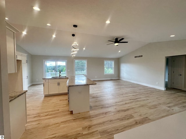 kitchen featuring light wood finished floors, visible vents, open floor plan, white cabinets, and vaulted ceiling