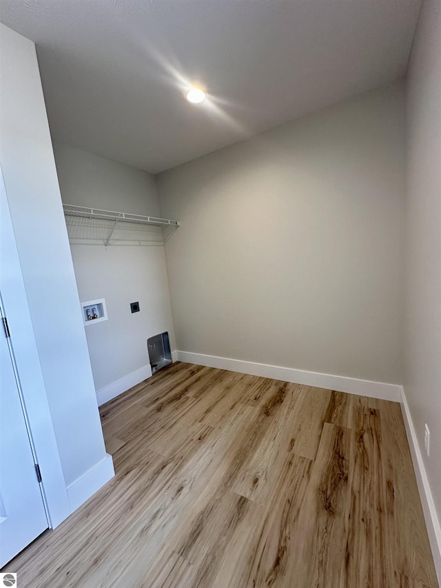 laundry area featuring laundry area, electric dryer hookup, baseboards, and wood finished floors