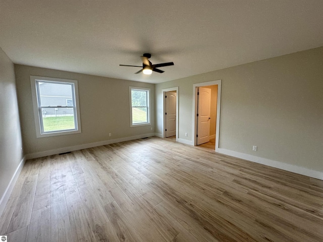 unfurnished bedroom with light wood-style floors, ceiling fan, and baseboards