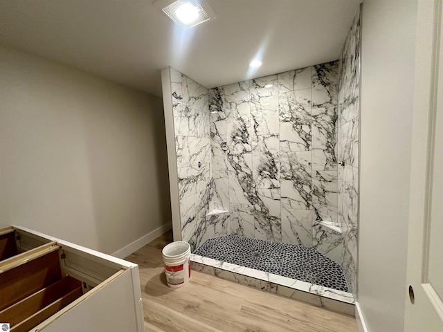 bathroom featuring a marble finish shower, baseboards, and wood finished floors