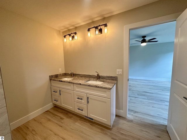 bathroom with a ceiling fan, a sink, baseboards, and wood finished floors