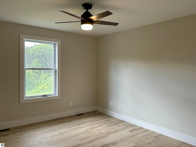 empty room with light wood finished floors, visible vents, and baseboards