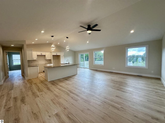 kitchen with open floor plan, white cabinetry, vaulted ceiling, and light wood finished floors