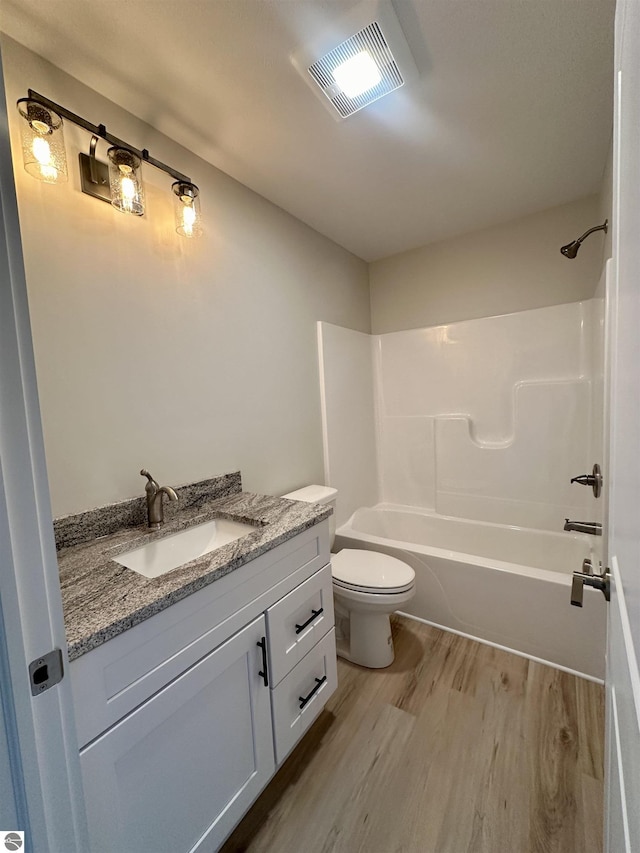 bathroom with toilet, vanity, wood finished floors, and visible vents