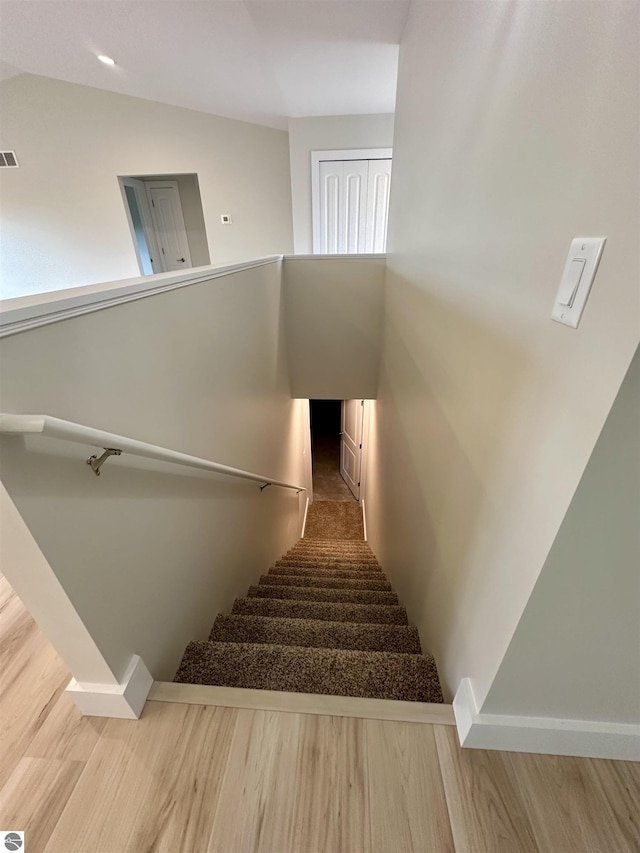 stairs with lofted ceiling, baseboards, visible vents, and wood finished floors