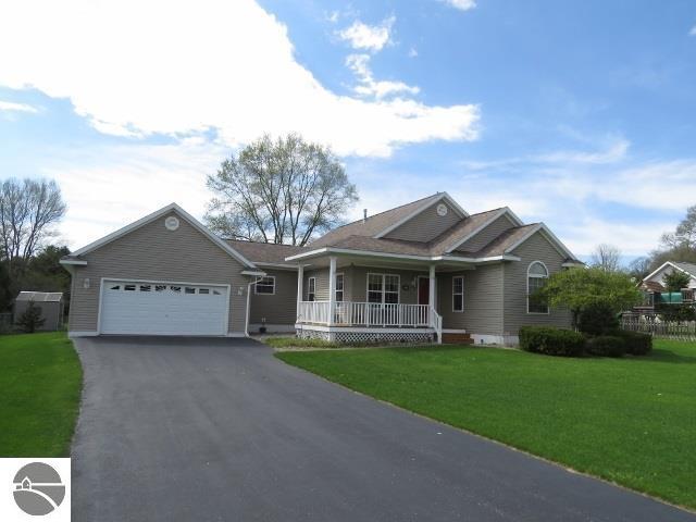 view of front of property featuring aphalt driveway, a front yard, covered porch, and an attached garage