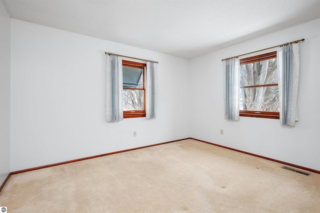 carpeted spare room featuring baseboards and visible vents