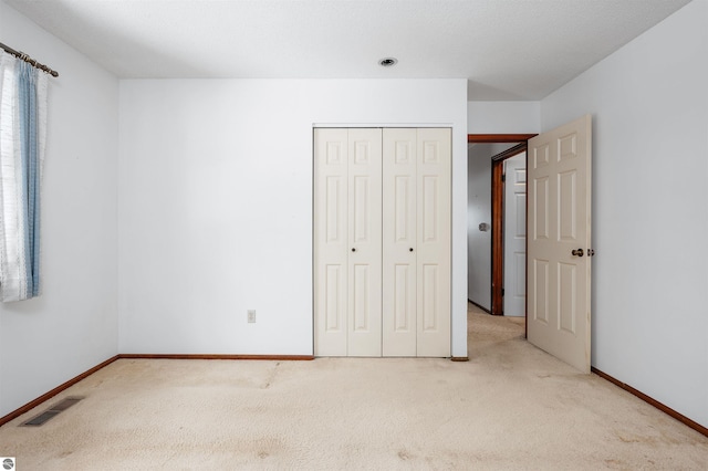 unfurnished bedroom featuring baseboards, carpet, visible vents, and a closet