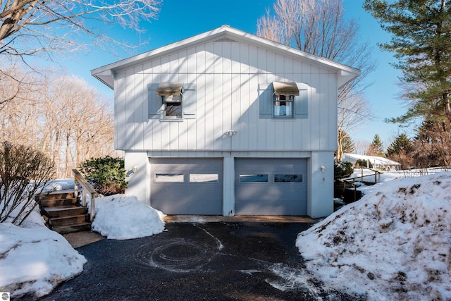 snow covered property featuring a garage and aphalt driveway