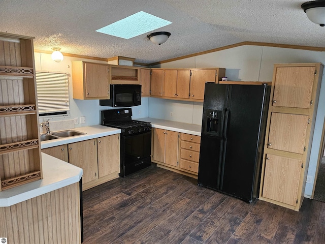 kitchen featuring vaulted ceiling with skylight, a sink, light countertops, ornamental molding, and black appliances