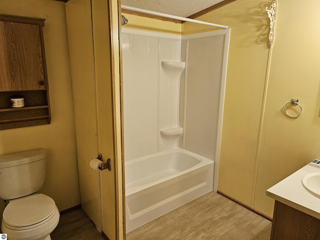 bathroom featuring toilet, wood finished floors, a textured ceiling, vanity, and shower / washtub combination