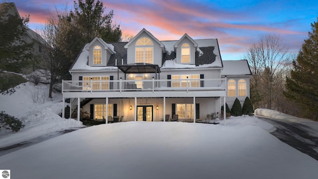 snow covered rear of property featuring french doors and a wooden deck