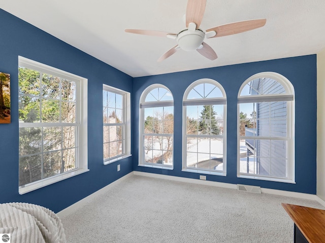 empty room featuring baseboards, visible vents, a wealth of natural light, and carpet flooring