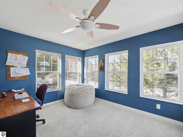 carpeted home office featuring a healthy amount of sunlight, a ceiling fan, baseboards, and a textured ceiling