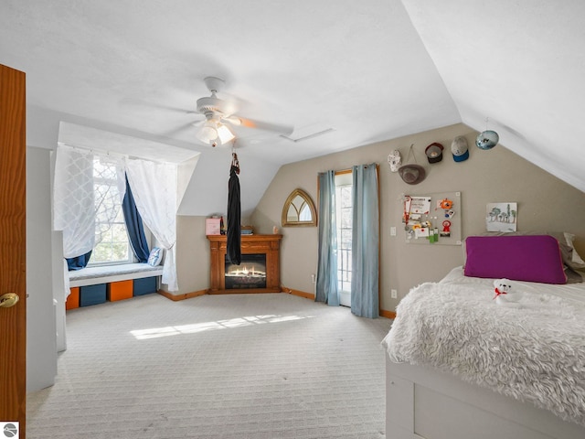 carpeted bedroom with vaulted ceiling, multiple windows, a glass covered fireplace, and baseboards