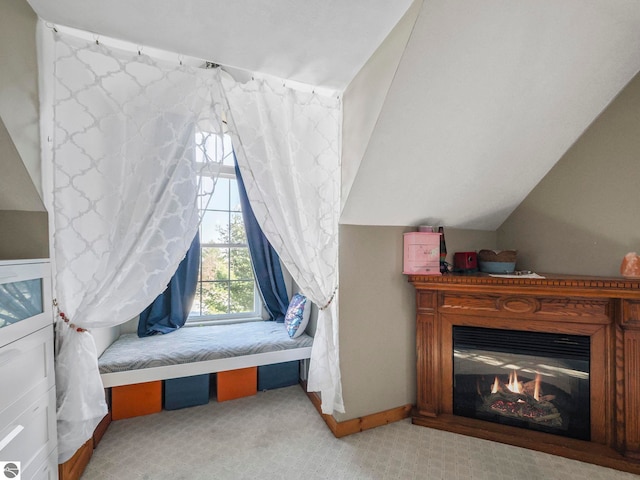 carpeted bedroom with lofted ceiling, a glass covered fireplace, and baseboards