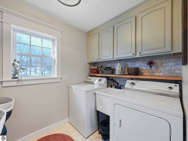 clothes washing area with baseboards, cabinet space, and washing machine and clothes dryer