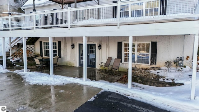 snow covered property entrance with a patio area