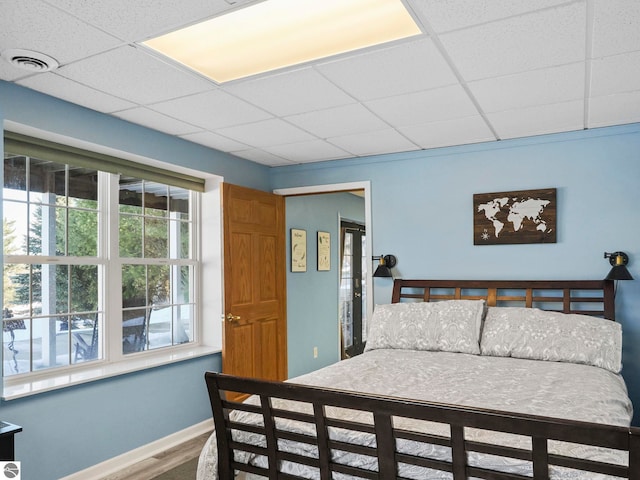 bedroom with visible vents, wood finished floors, a paneled ceiling, and baseboards