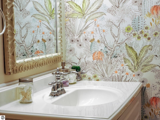 half bath with vanity and wallpapered walls