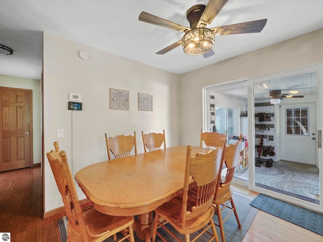 dining room with a ceiling fan, wood-type flooring, and baseboards