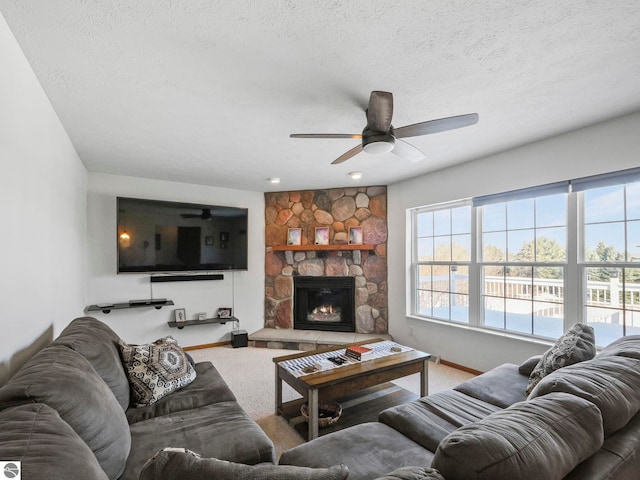 living room with a textured ceiling, a stone fireplace, plenty of natural light, and carpet flooring