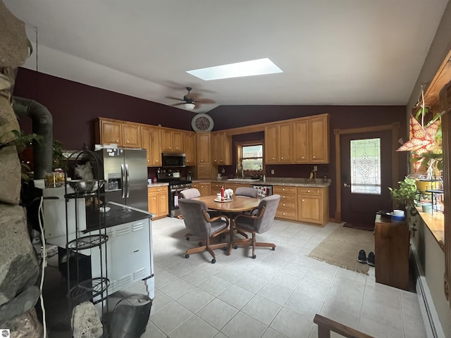 kitchen with light tile patterned floors, stainless steel appliances, baseboard heating, a sink, and vaulted ceiling with skylight