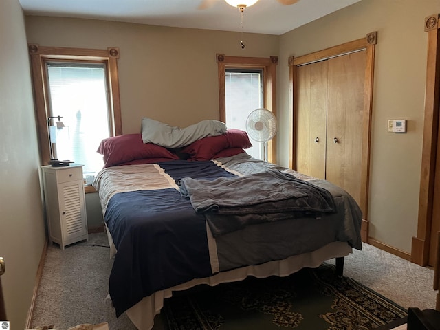 bedroom featuring a ceiling fan, a closet, light carpet, and baseboards