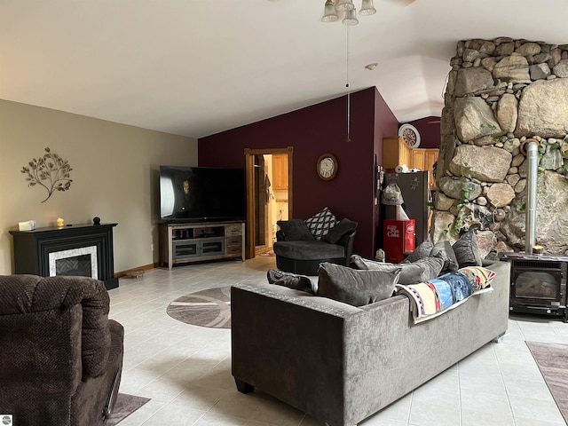 living area featuring lofted ceiling, light tile patterned flooring, and a wood stove