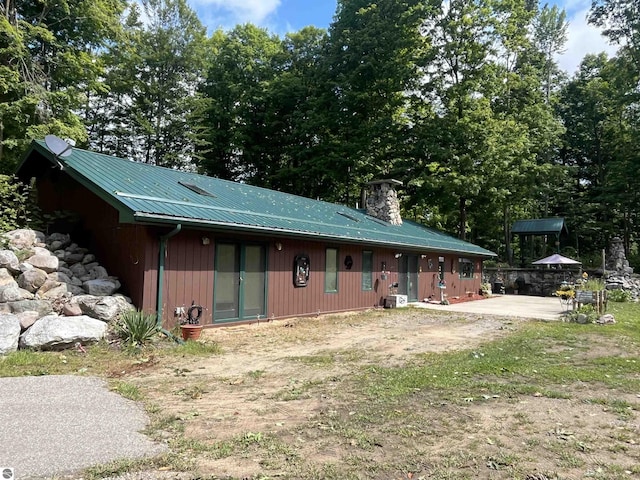 rear view of property with central AC, metal roof, a chimney, and a patio