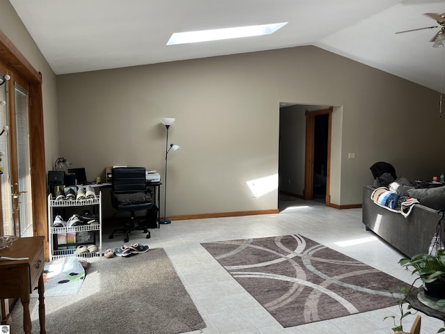 office area featuring lofted ceiling with skylight, ceiling fan, baseboards, and light tile patterned floors