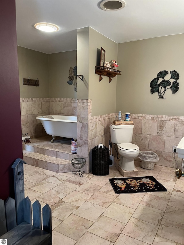 full bath with a soaking tub, a wainscoted wall, and tile walls