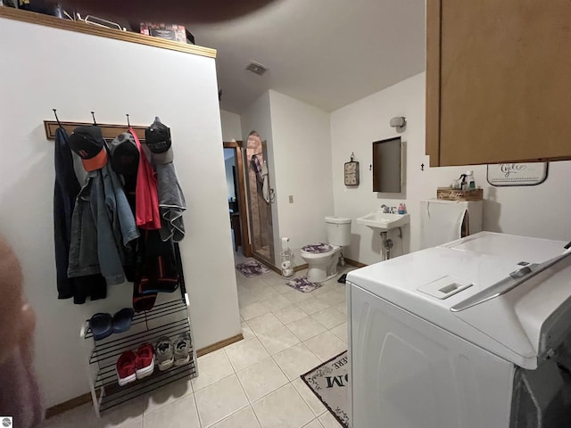 clothes washing area with laundry area, washer / clothes dryer, visible vents, and light tile patterned floors