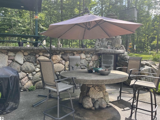 view of patio featuring a grill, outdoor dining area, and a view of trees