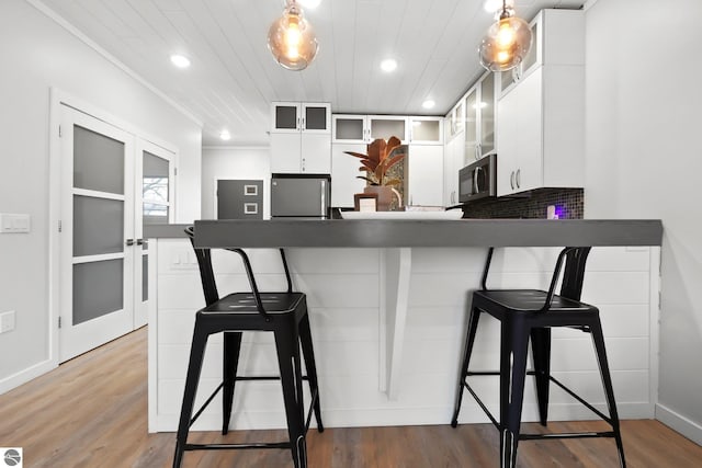 kitchen featuring french doors, appliances with stainless steel finishes, white cabinetry, a peninsula, and a kitchen breakfast bar