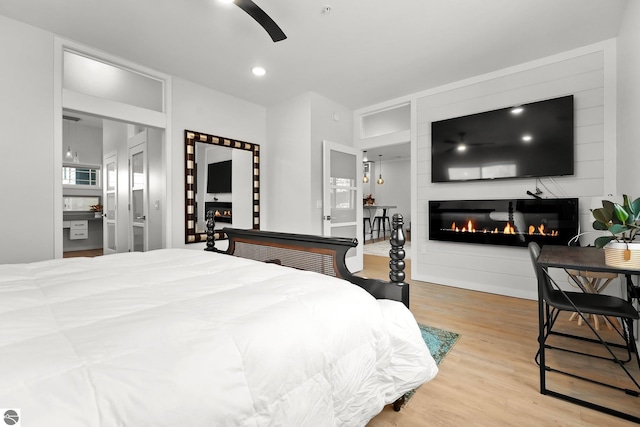 bedroom featuring a ceiling fan, recessed lighting, a fireplace, and wood finished floors