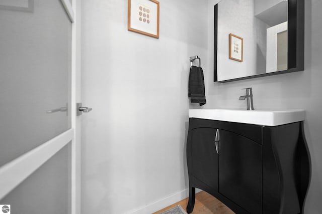 bathroom with baseboards, wood finished floors, and vanity