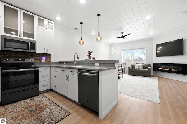 kitchen featuring dishwashing machine, a peninsula, black electric range, stainless steel microwave, and dark countertops