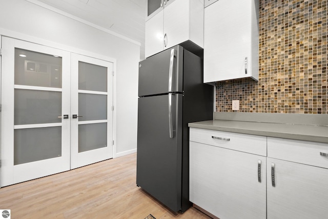 kitchen featuring white cabinetry, light wood-style floors, french doors, backsplash, and freestanding refrigerator