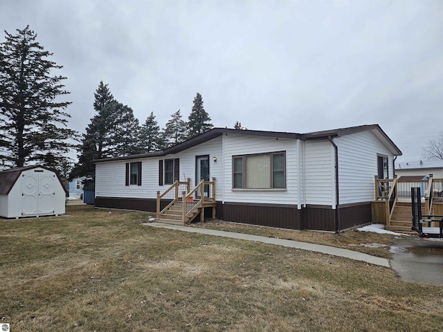 manufactured / mobile home featuring a wooden deck, a front yard, a storage unit, and an outdoor structure