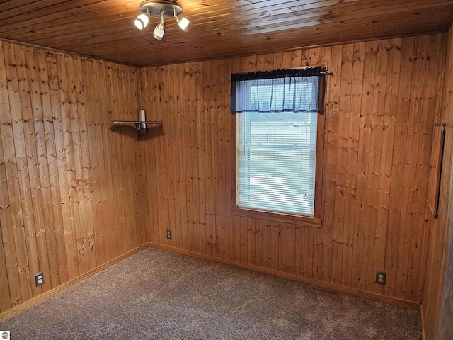 carpeted empty room with wood ceiling, wooden walls, and baseboards