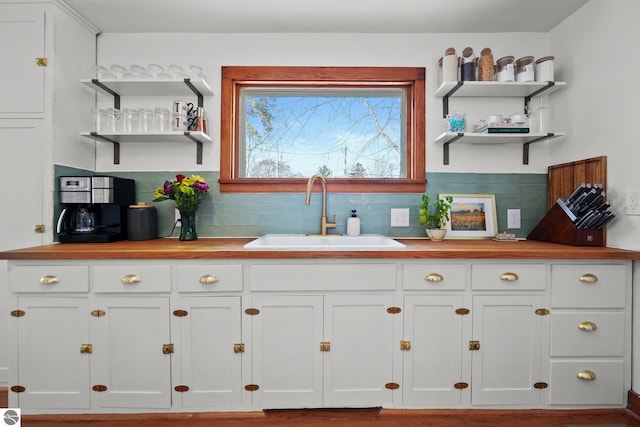 kitchen with white cabinetry, a sink, and open shelves