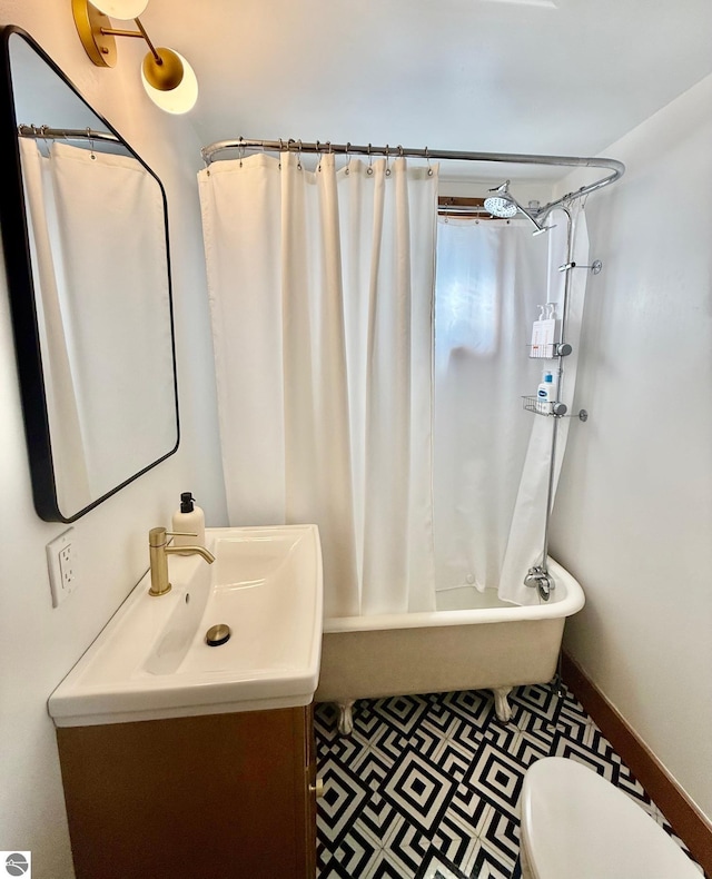 bathroom with toilet, baseboards, shower / tub combo with curtain, and vanity