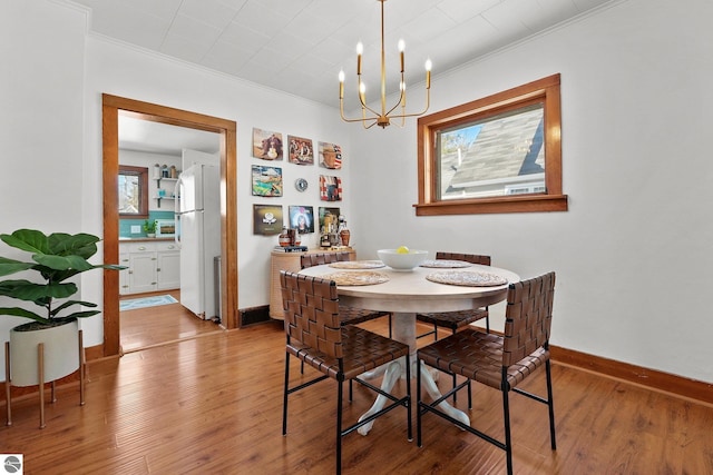 dining space with a notable chandelier, ornamental molding, wood finished floors, and baseboards