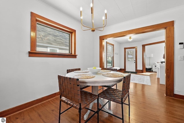 dining room with a healthy amount of sunlight, crown molding, baseboards, and hardwood / wood-style floors