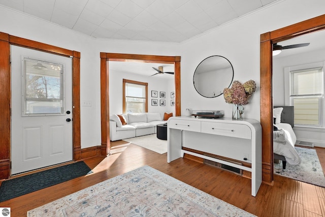 foyer with a healthy amount of sunlight, baseboards, ornamental molding, and wood finished floors