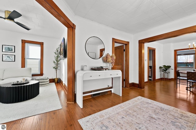 hallway with ornamental molding, a chandelier, baseboards, and hardwood / wood-style flooring