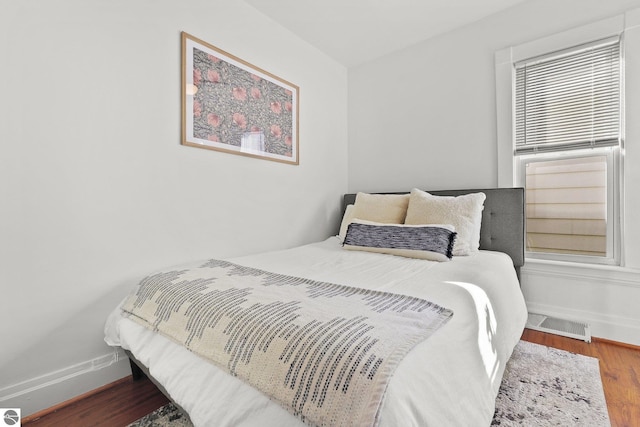 bedroom with wood finished floors, visible vents, and baseboards