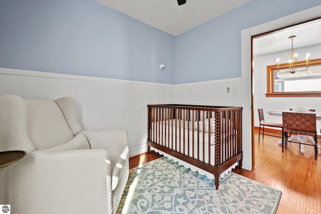 bedroom featuring ceiling fan with notable chandelier and wood finished floors